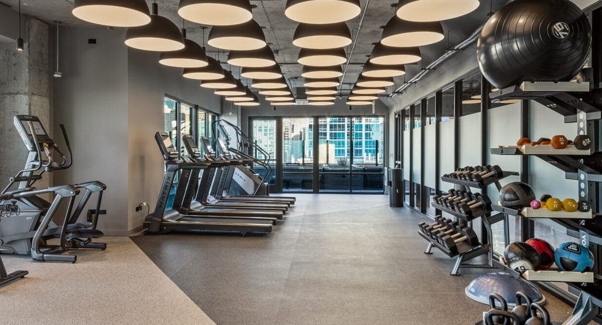 Expansive fitness center with a variety of cardio machines, free weights, and modern equipment at Hugo Apartments River North, Chicago