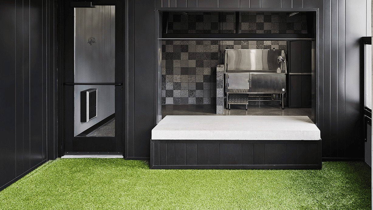 Indoor dog run area with artificial turf and a pet wash station, designed for convenience at Hugo Apartments River North, Chicago