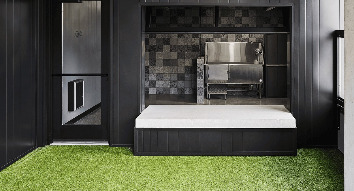 Indoor dog run area with artificial turf and a pet wash station, designed for convenience at Hugo Apartments River North, Chicago