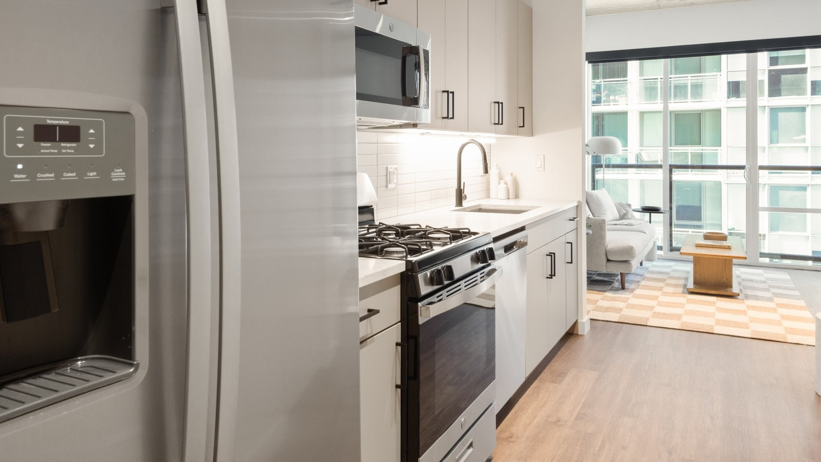 Contemporary kitchen with stainless steel appliances, ample counter space, and an open view into the living area at Hugo Apartments River North, Chicago