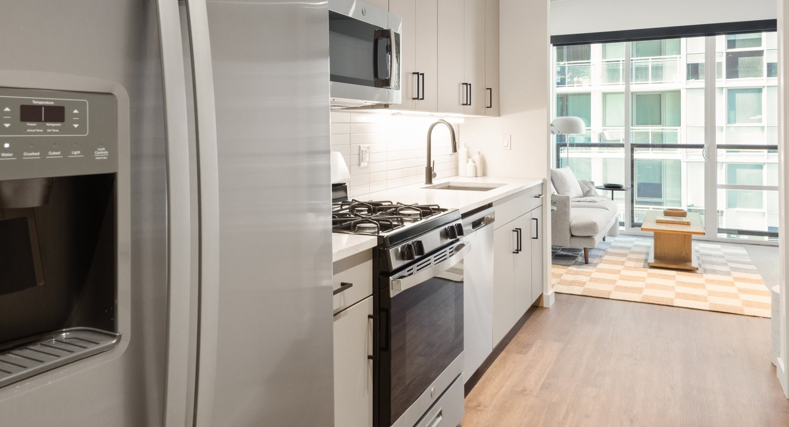 Contemporary kitchen with stainless steel appliances, ample counter space, and an open view into the living area at Hugo Apartments River North, Chicago