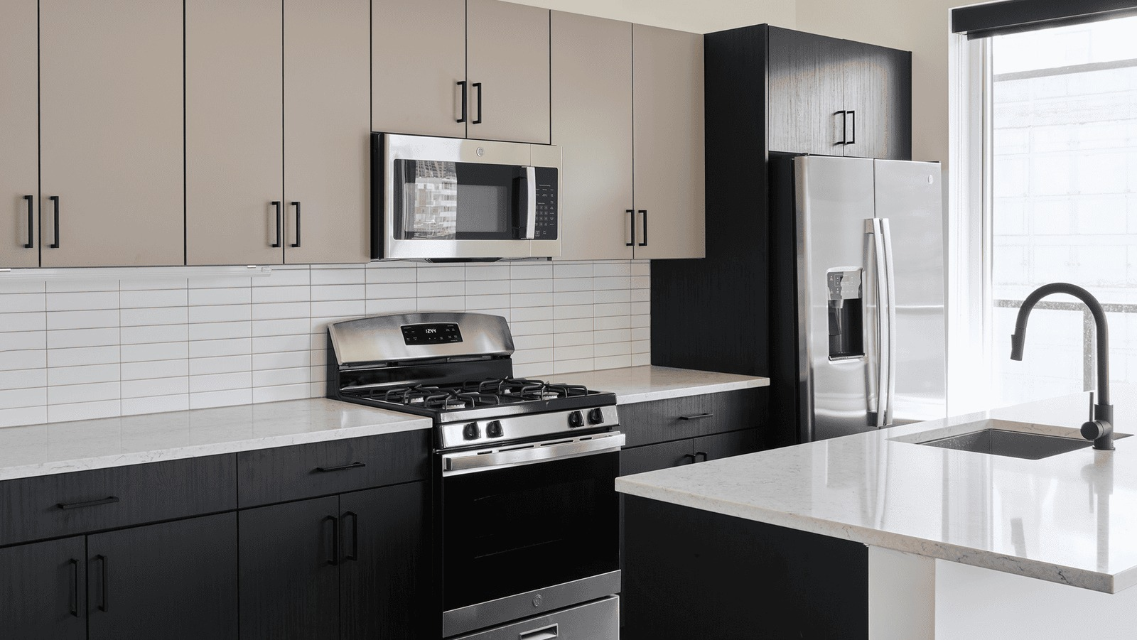 Modern kitchen with two-toned cabinetry, stainless steel appliances, and a white subway tile backsplash at Hugo Apartments River North, Chicago