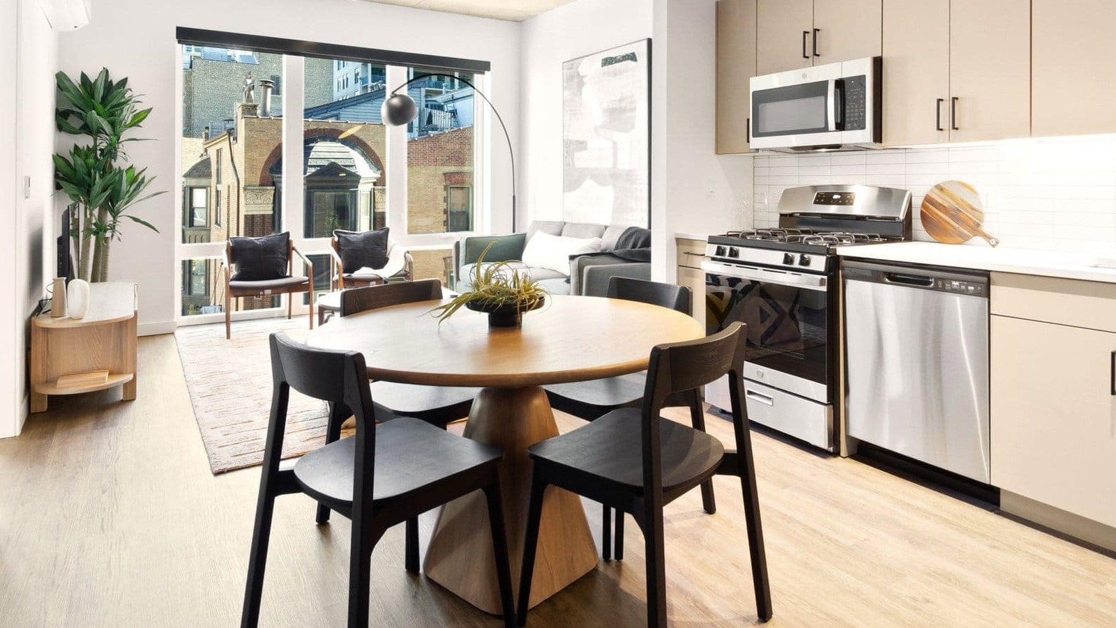 Bright open-concept kitchen and dining area with modern lighting, light wood floors, and neutral tones at Hugo Apartments River North, Chicago