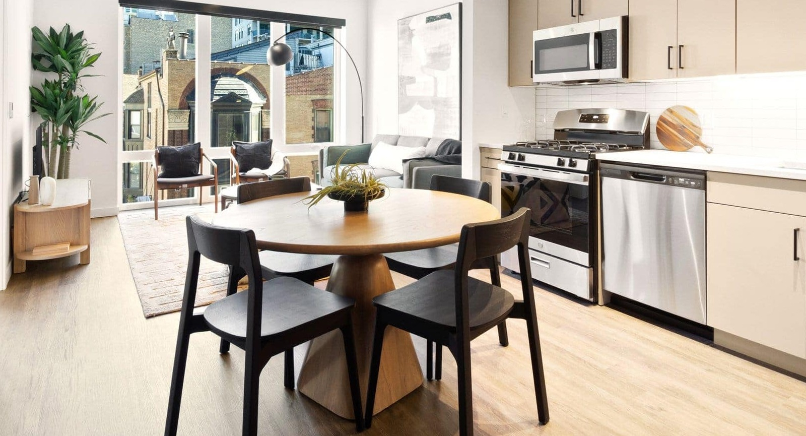 Bright open-concept kitchen and dining area with modern lighting, light wood floors, and neutral tones at Hugo Apartments River North, Chicago