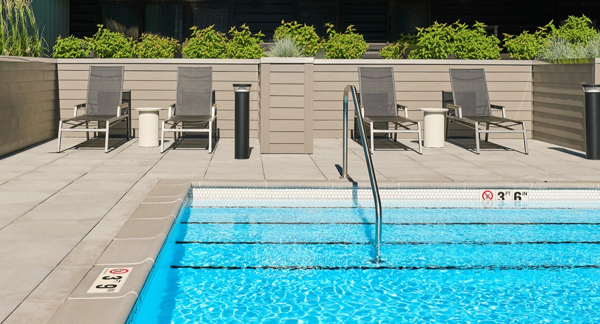 Sparkling outdoor swimming pool with lounge chairs and the apartment building facade in the background at Hugo Apartments River North, Chicago
