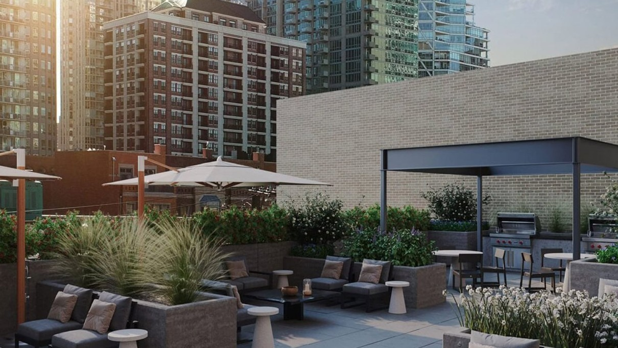 Scenic rooftop lounge with comfortable seating, umbrellas, and BBQ grills, offering city views at Hugo Apartments River North, Chicago
