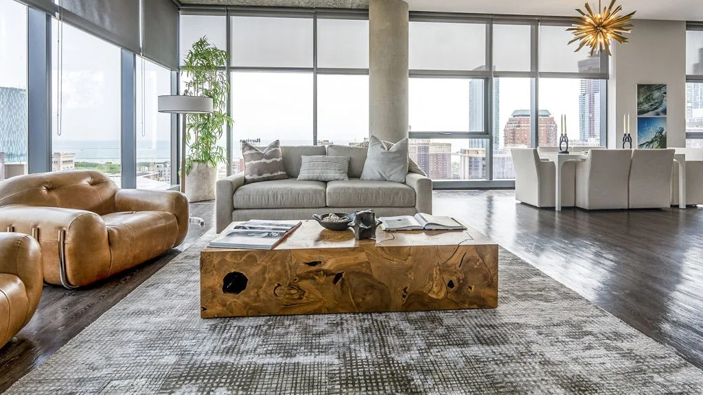 Expansive open-concept living and dining area with modern furniture and floor-to-ceiling windows displaying city views at Imprint apartments in Chicago