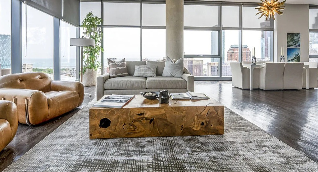 Expansive open-concept living and dining area with modern furniture and floor-to-ceiling windows displaying city views at Imprint apartments in Chicago