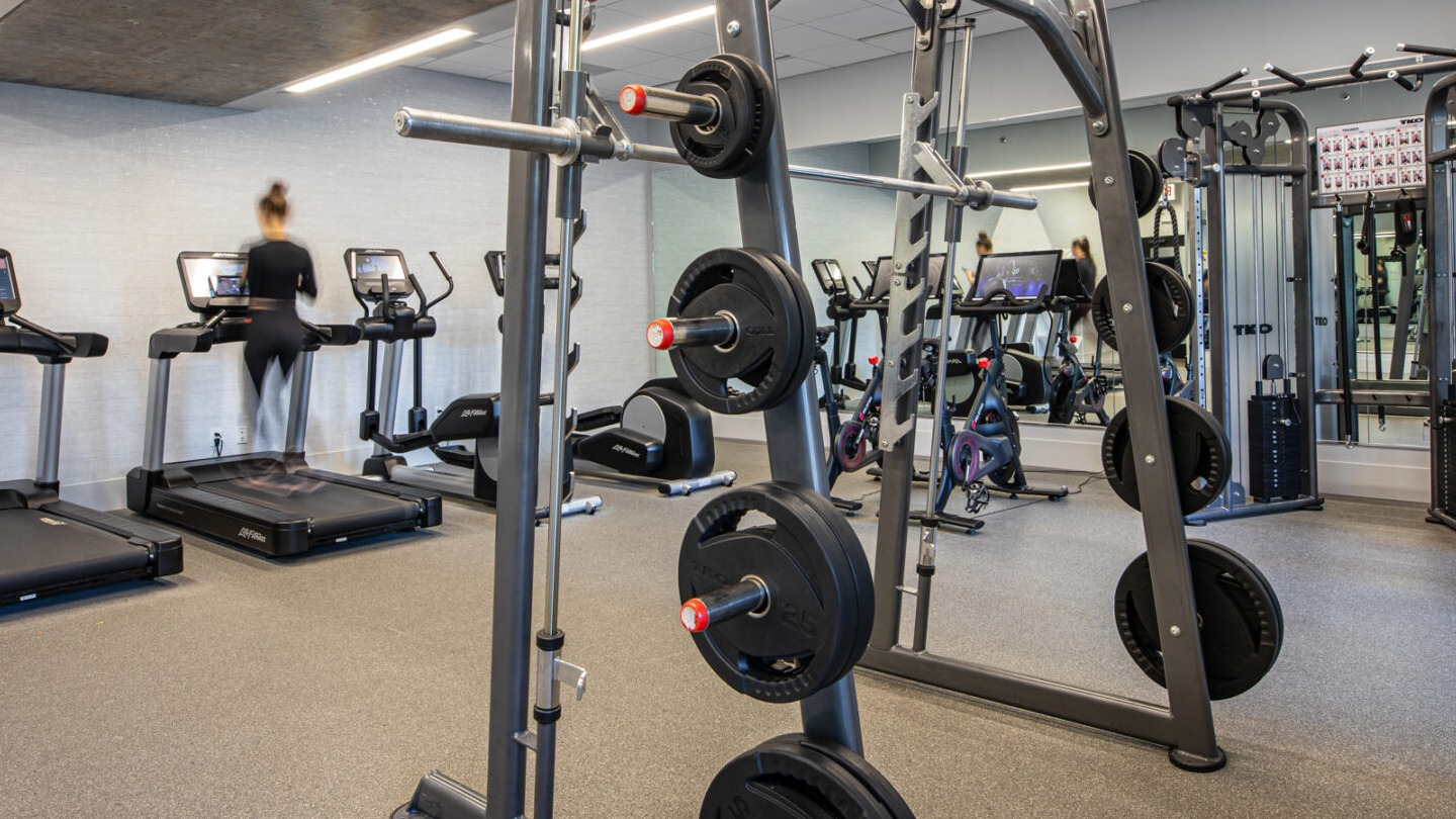 State-of-the-art fitness center with treadmills, weight racks, and various exercise machines at Imprint apartments in Chicago