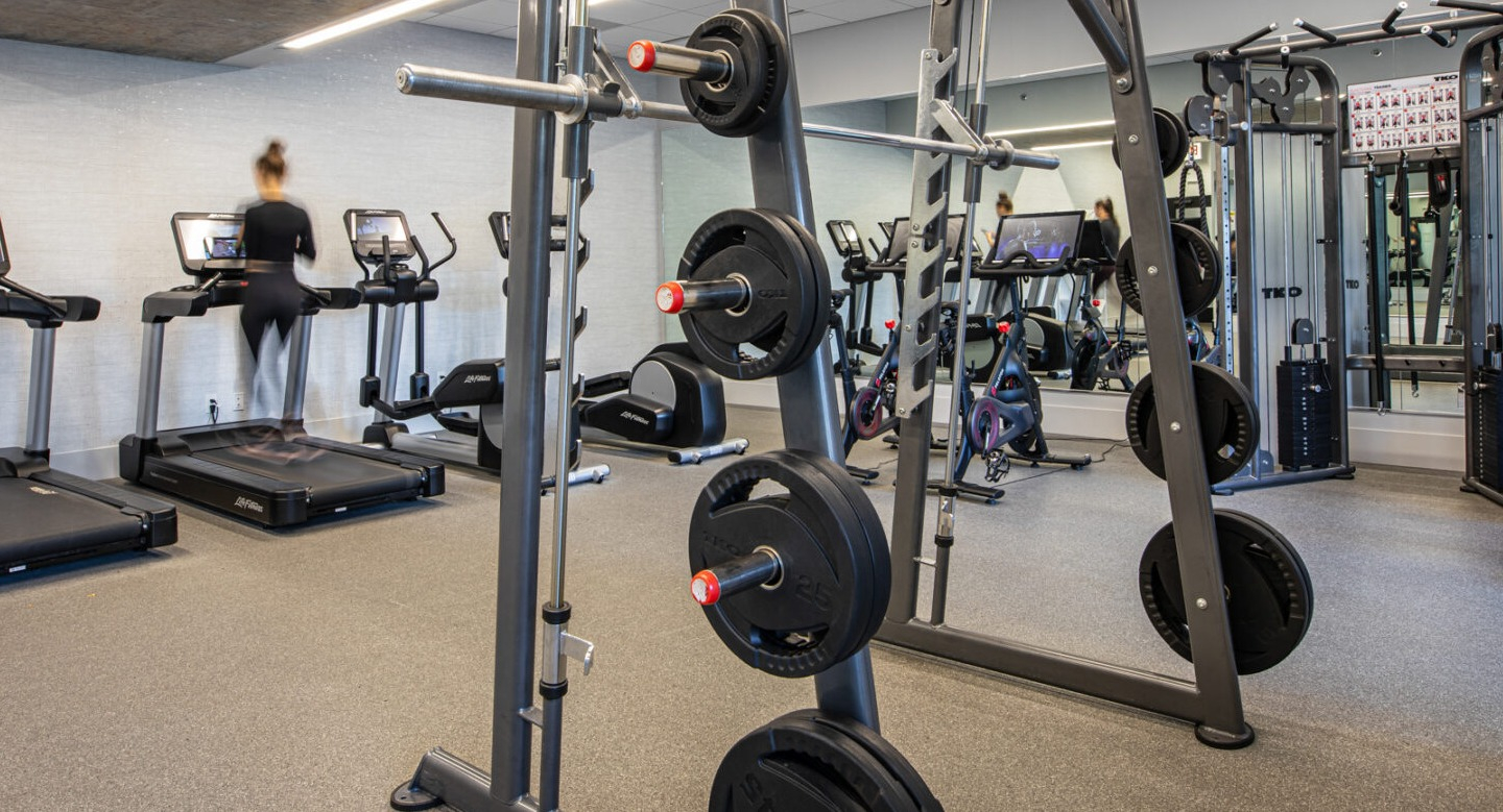 State-of-the-art fitness center with treadmills, weight racks, and various exercise machines at Imprint apartments in Chicago