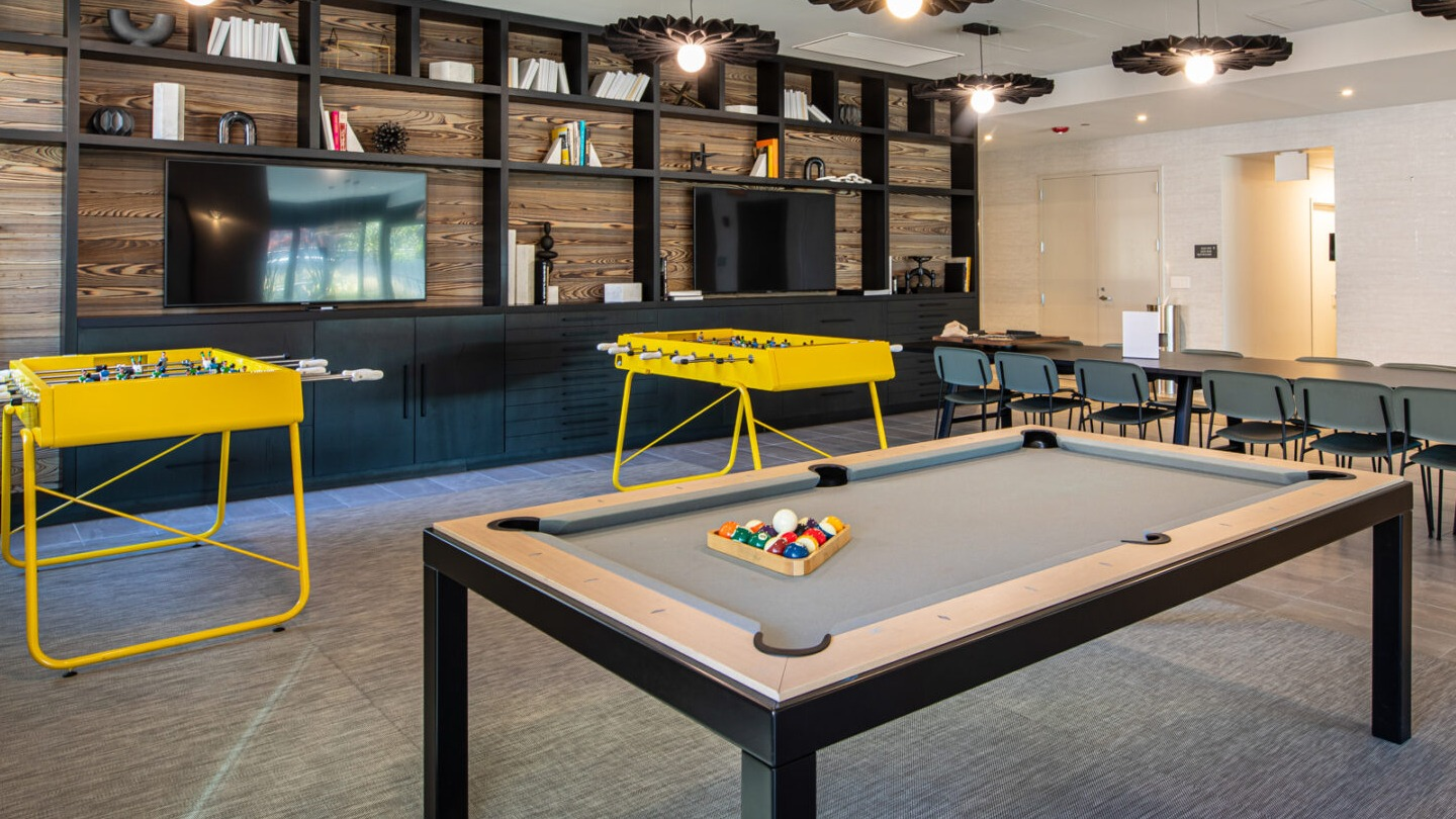 Exciting game room with a billiards table, foosball tables, and cozy seating areas, perfect for entertainment at Imprint apartments in Chicago