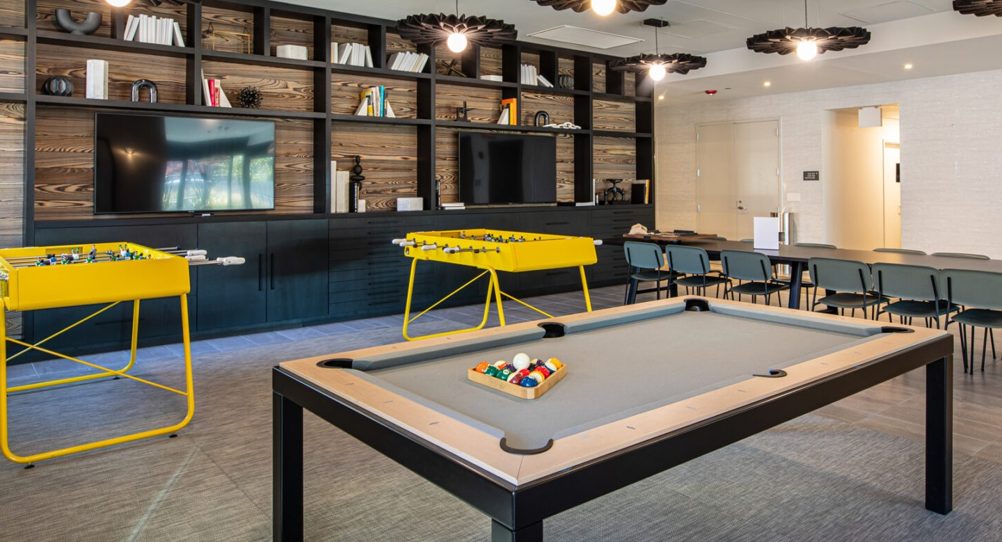 Exciting game room with a billiards table, foosball tables, and cozy seating areas, perfect for entertainment at Imprint apartments in Chicago