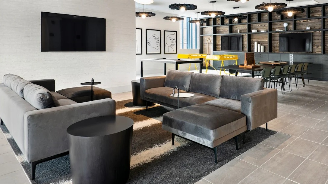 Expansive resident lounge with comfortable sofas, a large TV, and co-working tables and chairs at Imprint apartments in Chicago