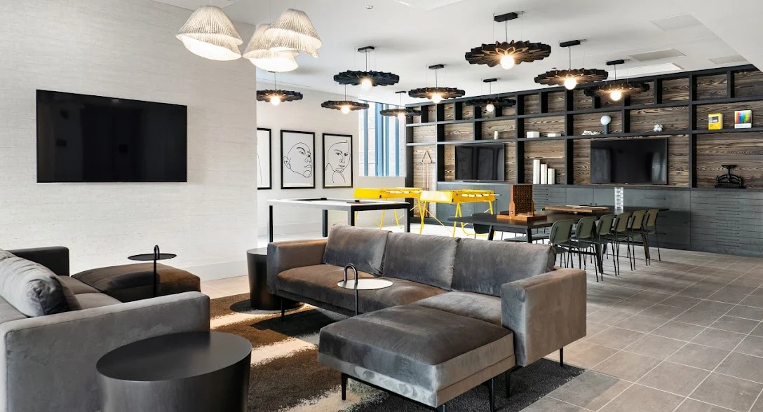 Expansive resident lounge with comfortable sofas, a large TV, and co-working tables and chairs at Imprint apartments in Chicago