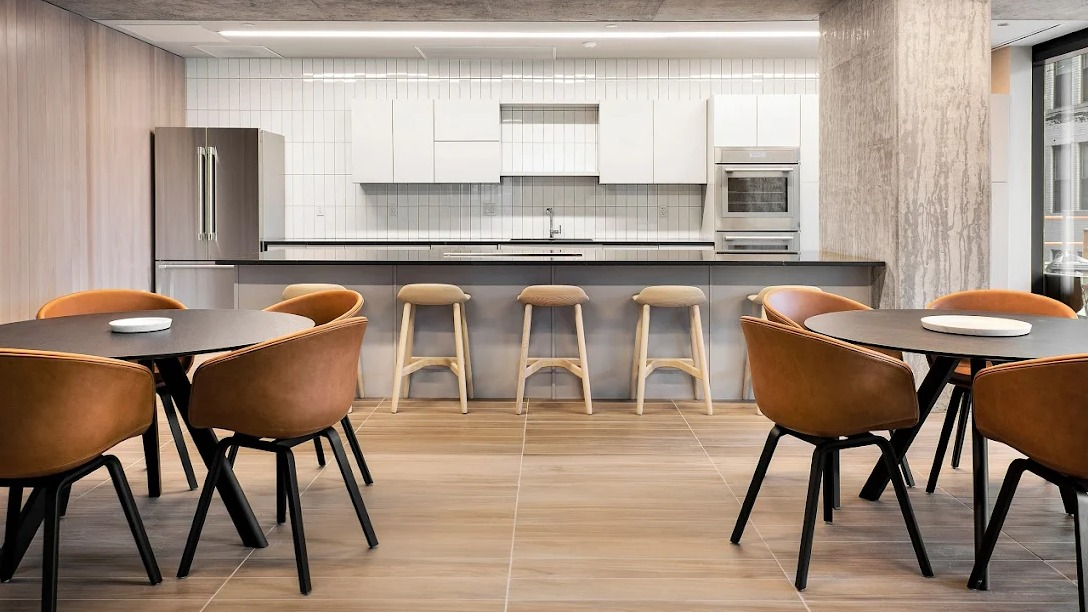 Modern resident kitchen with a large island, bar seating, and multiple dining tables in a spacious common area at Imprint apartments in Chicago