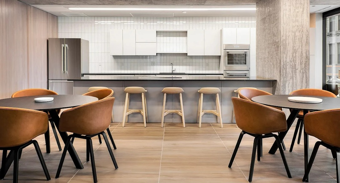 Modern resident kitchen with a large island, bar seating, and multiple dining tables in a spacious common area at Imprint apartments in Chicago