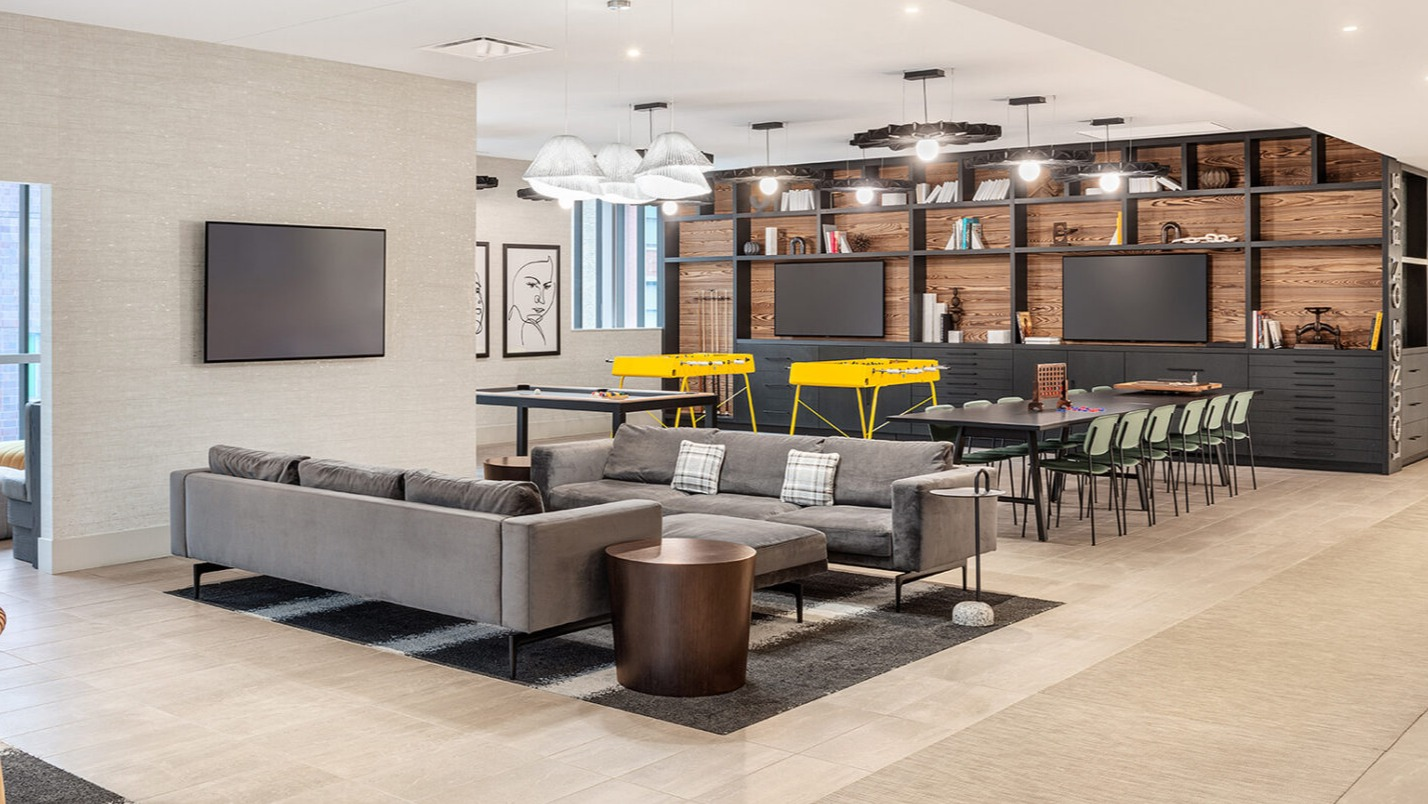 Spacious resident lounge featuring comfortable sofas, a TV area, and a dedicated game area with foosball tables at Imprint apartments in Chicago