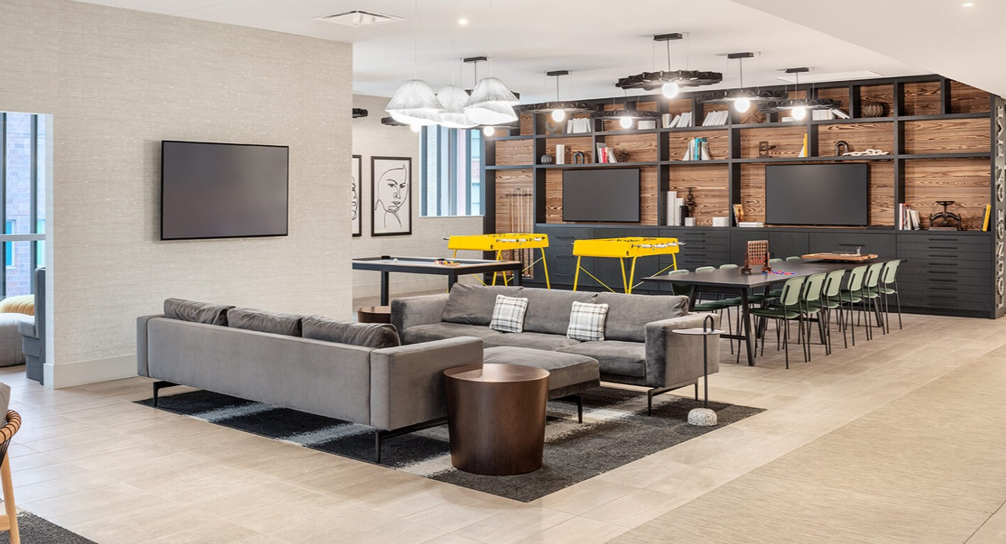 Spacious resident lounge featuring comfortable sofas, a TV area, and a dedicated game area with foosball tables at Imprint apartments in Chicago