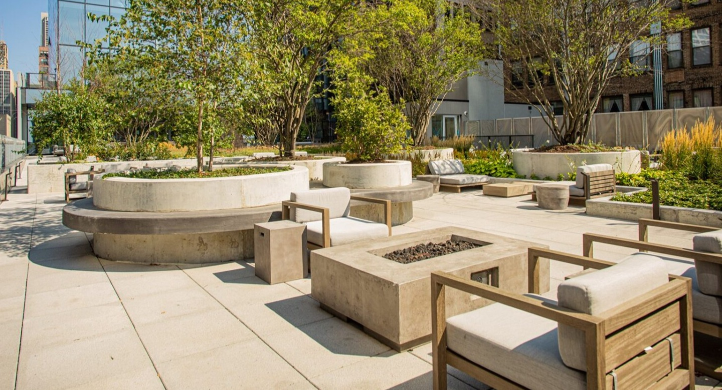 Lush rooftop patio with comfortable outdoor seating, a modern fire pit, and beautiful landscaping at Imprint apartments in Chicago
