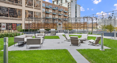 Beautifully landscaped outdoor courtyard with diverse seating areas, green spaces, and BBQ grills for residents at JeffJack Apartments in Chicago