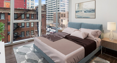 Cozy bedroom with a comfortable bed, warm decor, and large windows offering urban city views at JeffJack Apartments in Chicago