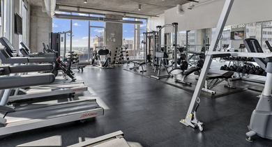 Spacious fitness center with a variety of cardio machines, free weights, and strength training equipment at JeffJack Apartments in Chicago