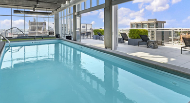 Stunning indoor-outdoor pool area with a swimming pool, lounge chairs, and city views at JeffJack Apartments in Chicago