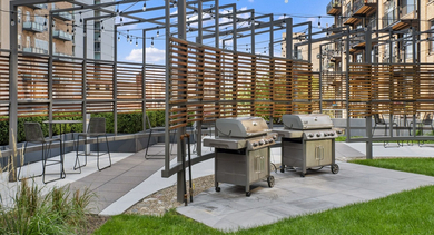 Modern outdoor grilling stations with multiple BBQs and bar seating within a well-maintained courtyard at JeffJack Apartments in Chicago