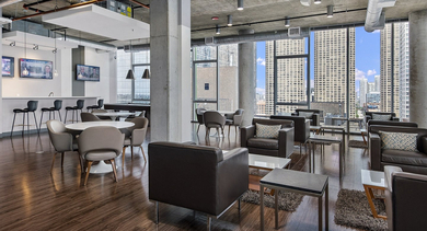 Contemporary resident lounge with comfortable seating, dining tables, and large windows showcasing city views at JeffJack Apartments in Chicago