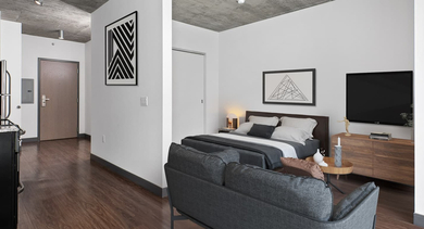 Efficient studio apartment layout featuring a combined living and sleeping area with modern furniture and a compact kitchen at JeffJack Apartments in Chicago