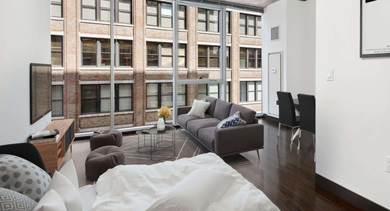 Spacious studio apartment with an open layout, featuring distinct sleeping and living areas, and large windows at JeffJack Apartments in Chicago