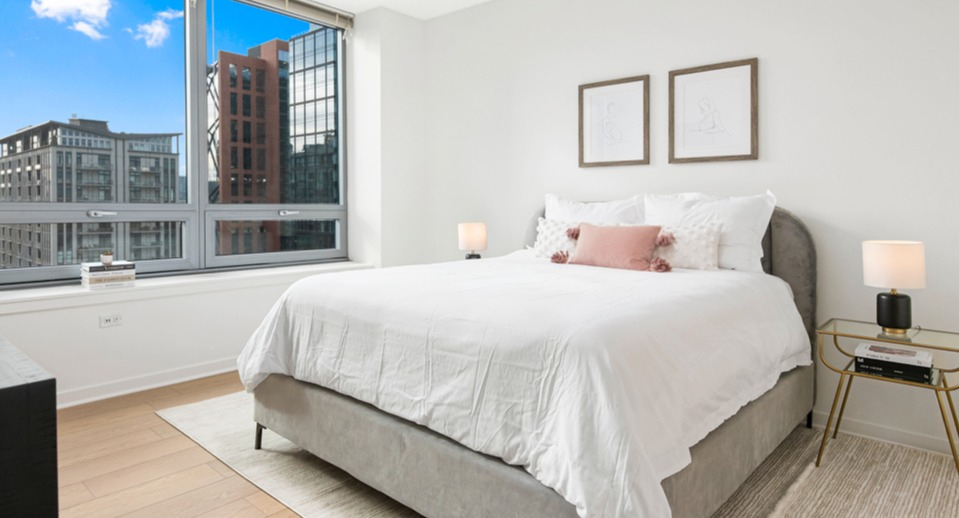 Serene apartment bedroom with a comfortable bed, stylish decor, and expansive windows offering captivating city views at K2 Apartments in Chicago