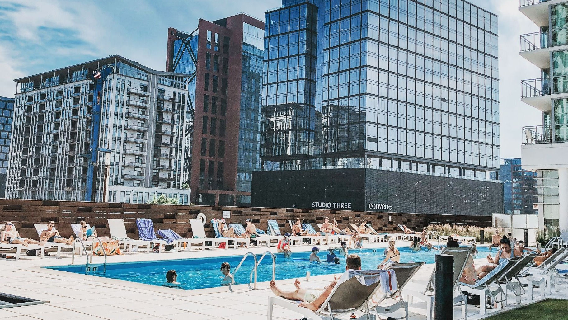 Inviting outdoor swimming pool surrounded by lounge chairs, with residents enjoying the sun and cityscape views at K2 Apartments in Chicago