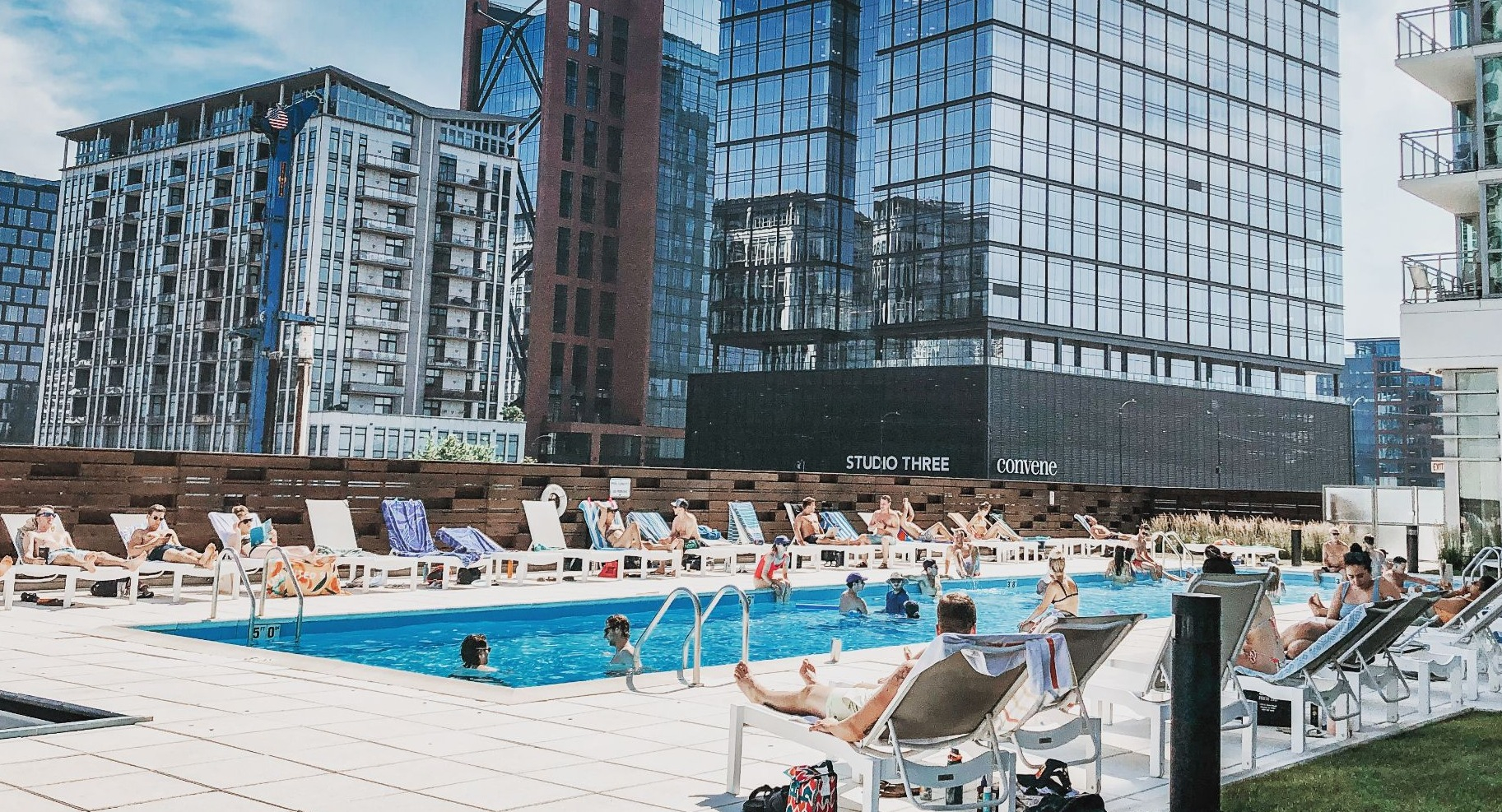 Inviting outdoor swimming pool surrounded by lounge chairs, with residents enjoying the sun and cityscape views at K2 Apartments in Chicago