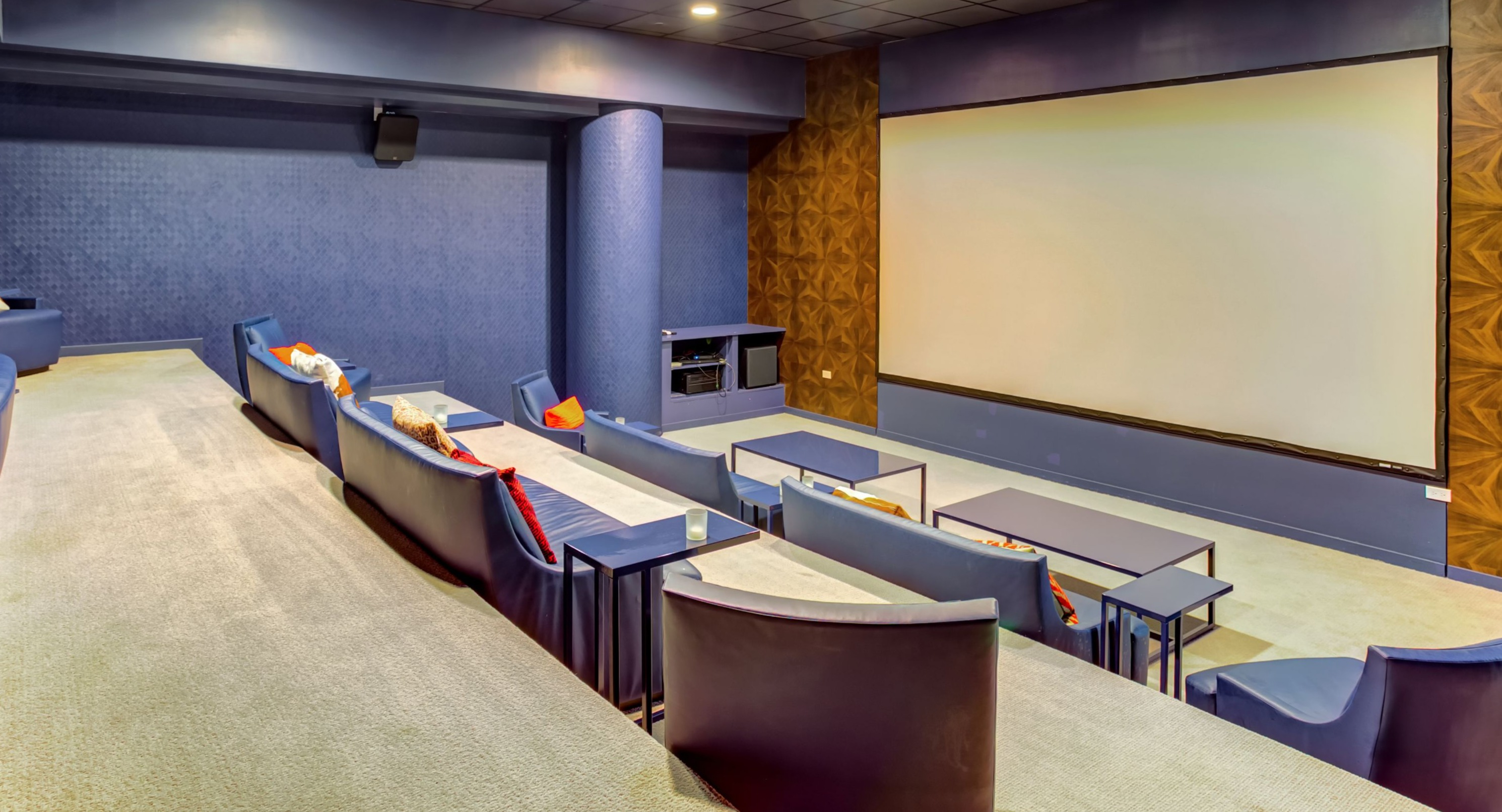 Luxurious private movie theater with comfortable tiered seating and a large projection screen, perfect for film nights at K2 Apartments in Chicago