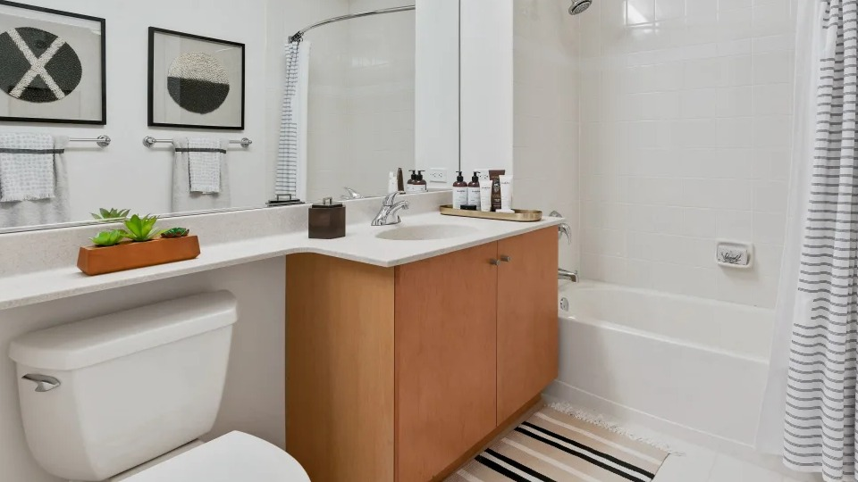 Classic bathroom with a vanity, large mirror, and a shower-tub combination with white subway tiles at Kingsbury Plaza in Chicago