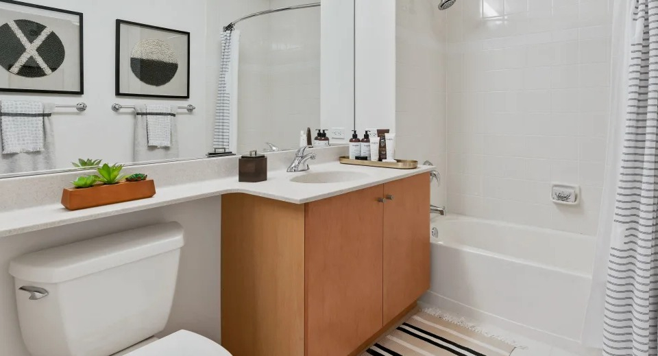 Classic bathroom with a vanity, large mirror, and a shower-tub combination with white subway tiles at Kingsbury Plaza in Chicago