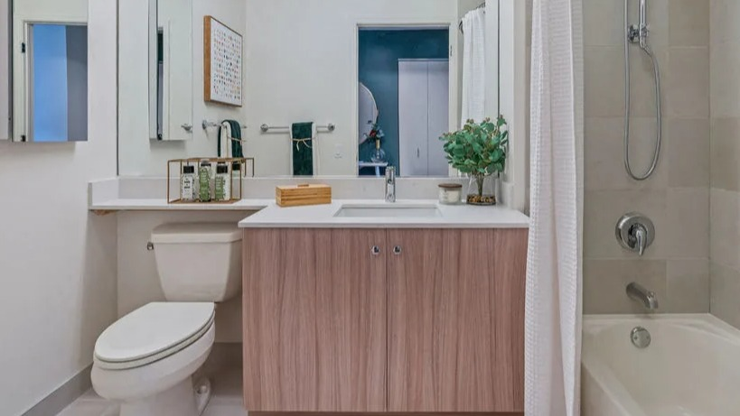 Contemporary bathroom with a light wood vanity, large mirror, and a shower-tub combination featuring tiled walls at Kingsbury Plaza in Chicago