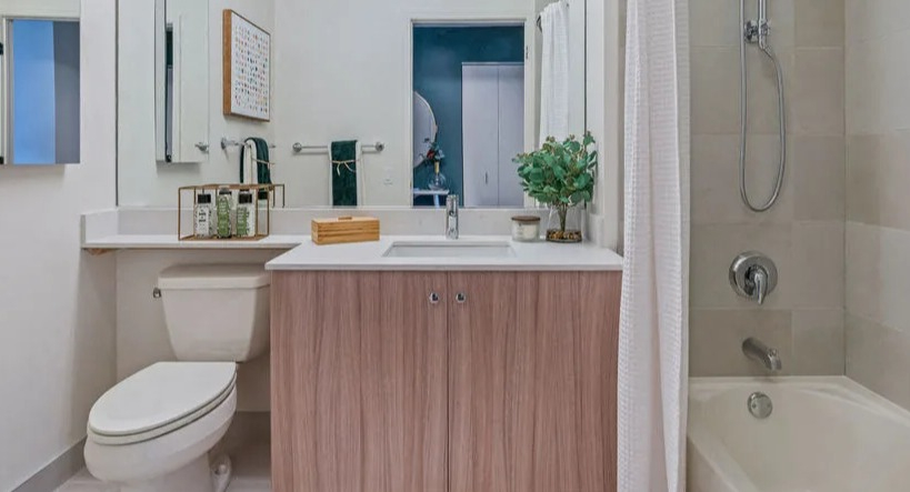 Contemporary bathroom with a light wood vanity, large mirror, and a shower-tub combination featuring tiled walls at Kingsbury Plaza in Chicago