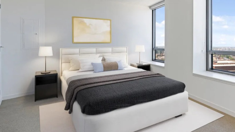 Bright bedroom with a comfortable bed, minimalist decor, and large windows offering expansive city views at Kingsbury Plaza in Chicago