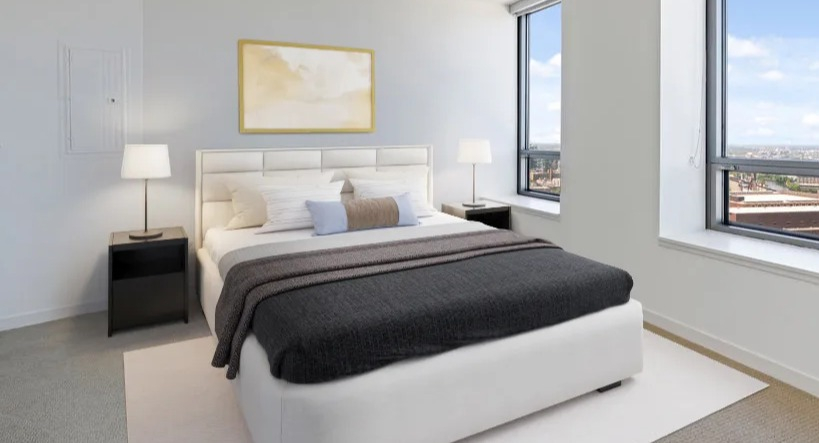 Bright bedroom with a comfortable bed, minimalist decor, and large windows offering expansive city views at Kingsbury Plaza in Chicago