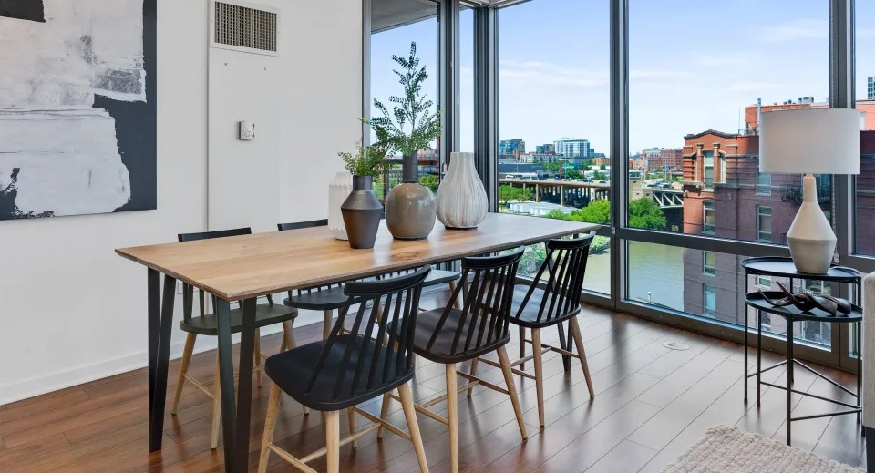 Modern dining and living room with a large table, comfortable seating, and expansive windows offering river views at Kingsbury Plaza in Chicago