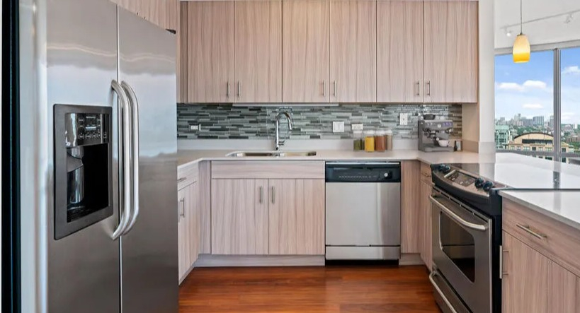 Modern kitchen with a large island, stainless steel appliances, light wood cabinetry, and an open layout at Kingsbury Plaza in Chicago