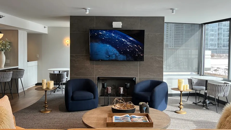 Kingsbury Plaza resident lounge with a cozy fireplace, large TV, comfortable seating, and city views