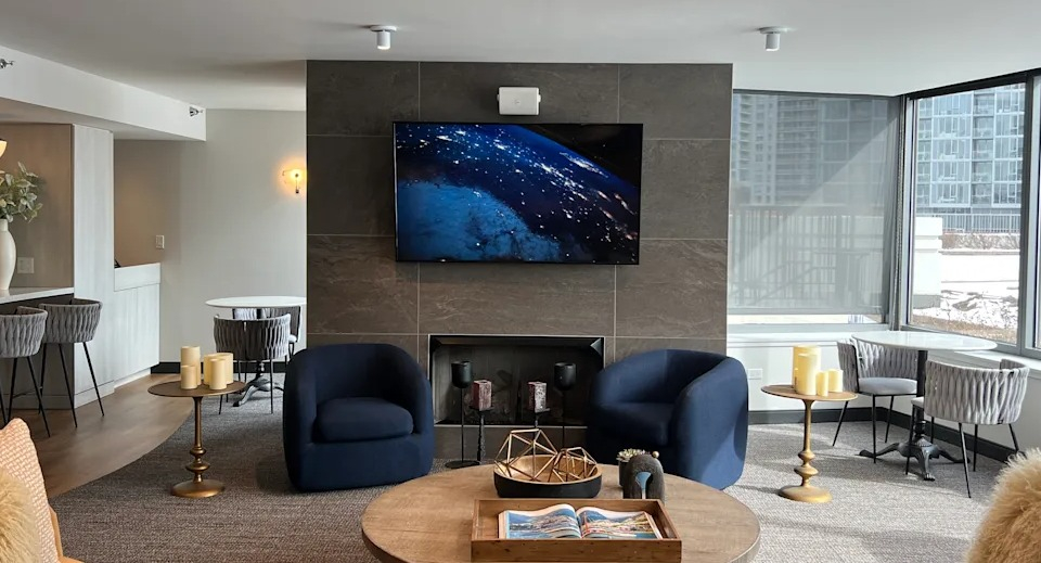 Kingsbury Plaza resident lounge with a cozy fireplace, large TV, comfortable seating, and city views