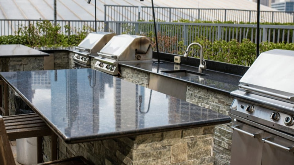 Modern outdoor grilling station with multiple gas grills, granite countertops, and bar seating for residents at Kingsbury Plaza in Chicago