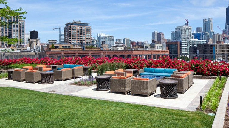 Kingsbury Plaza outdoor terrace with comfortable lounge seating, lush landscaping, and vibrant city skyline views