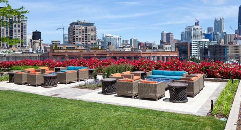 Kingsbury Plaza outdoor terrace with comfortable lounge seating, lush landscaping, and vibrant city skyline views