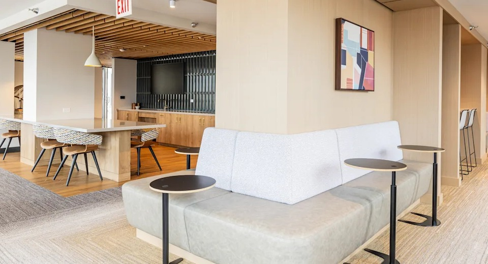 Modern co-working space at Kingsbury Plaza, featuring comfortable seating, tables, and a communal kitchen area