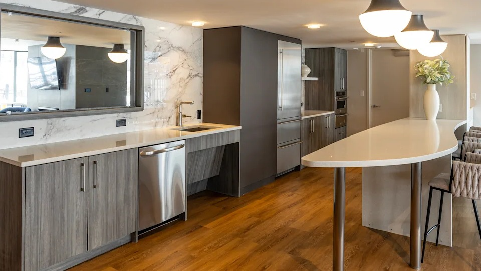 Sophisticated resident lounge with a full kitchen, long bar with seating, and a large mirror, ideal for social gatherings at Kingsbury Plaza in Chicago
